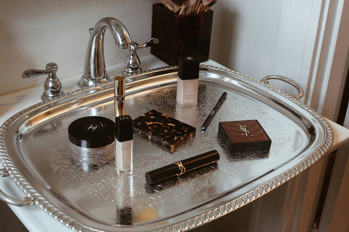 beauty essential tray holding makeup brushes, lipsticks, and skincare minis on a clean vanity